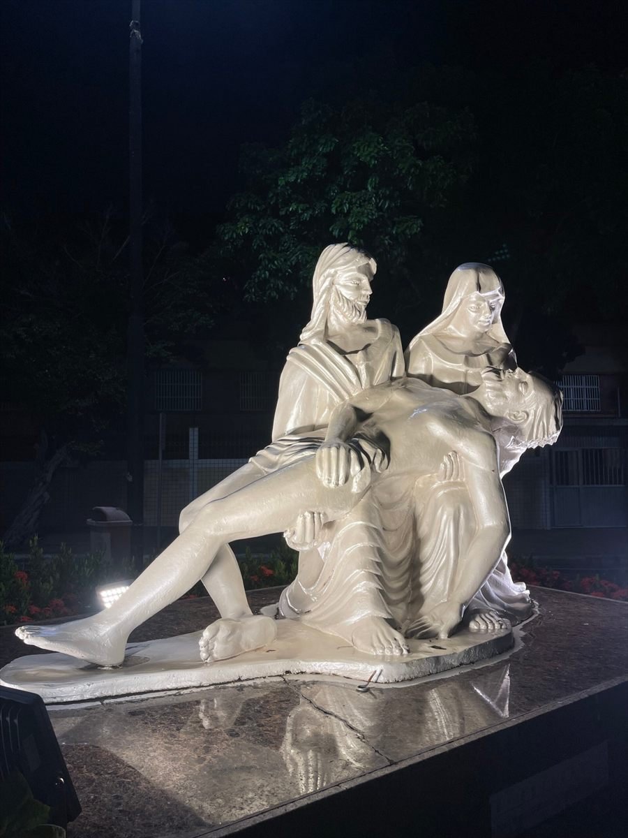 Escultura de figuras sentadas iluminada à noite